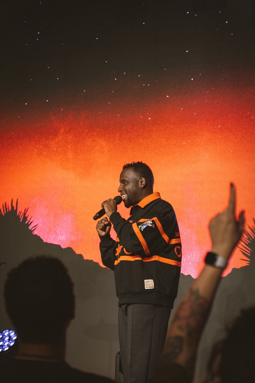 Peter Reeves speaking on stage in front of a glowing orange backdrop